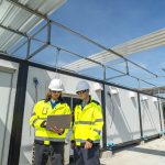 Ein Ingenieur mit Sichtschutzjacke und Helm arbeitet auf der Baustelle.